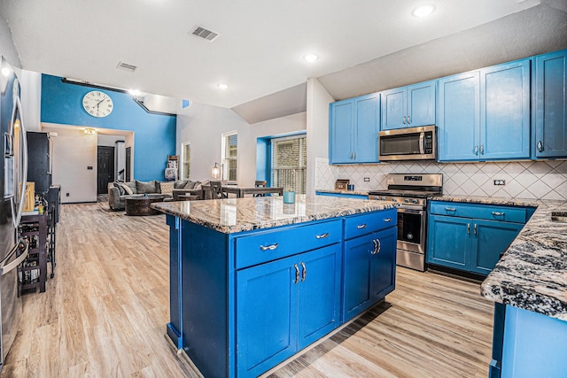 kitchen featuring visible vents, appliances with stainless steel finishes, stone countertops, open floor plan, and blue cabinets