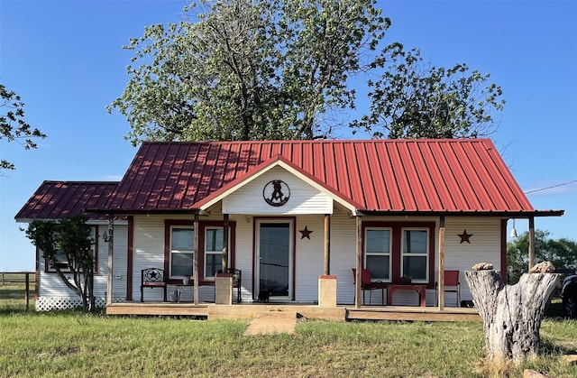 view of front of home featuring covered porch, metal roof, and a front lawn