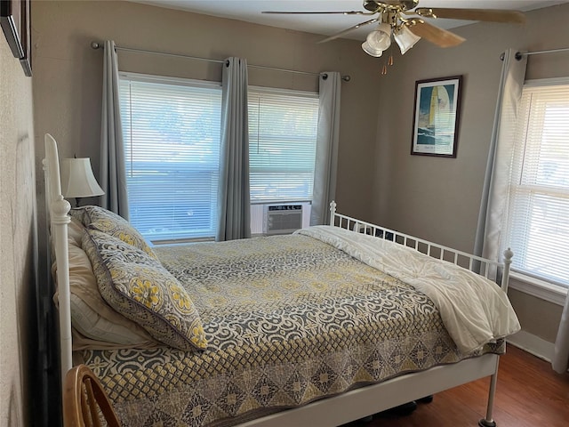 bedroom featuring a ceiling fan, cooling unit, baseboards, and wood finished floors