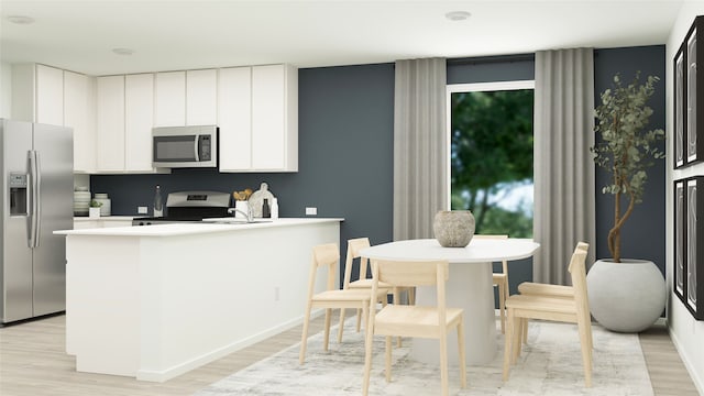 kitchen with a peninsula, appliances with stainless steel finishes, light countertops, white cabinets, and light wood-style floors