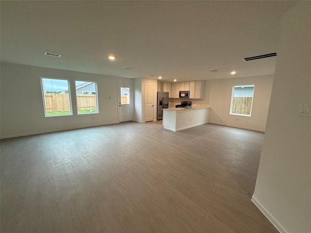 unfurnished living room with baseboards, recessed lighting, light wood-type flooring, and visible vents