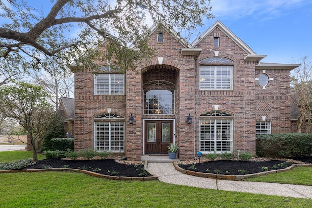 view of front of property featuring french doors, a front lawn, and brick siding