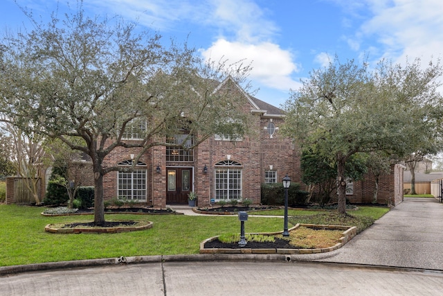 colonial-style house with a front yard, brick siding, and fence