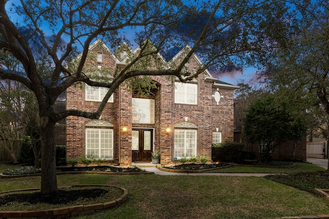 traditional-style home with french doors, a front lawn, and brick siding