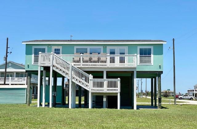 back of house with a carport, a yard, and stairs