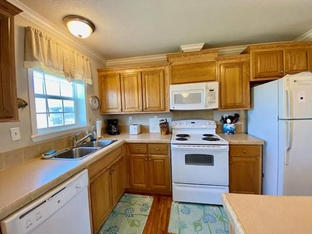 kitchen featuring ornamental molding, white appliances, light countertops, and a sink