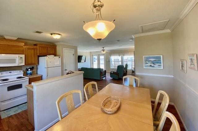 dining room with dark wood-type flooring, visible vents, crown molding, and baseboards