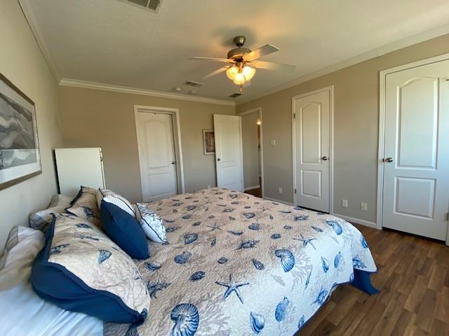 bedroom featuring baseboards, ceiling fan, dark wood-style flooring, and crown molding