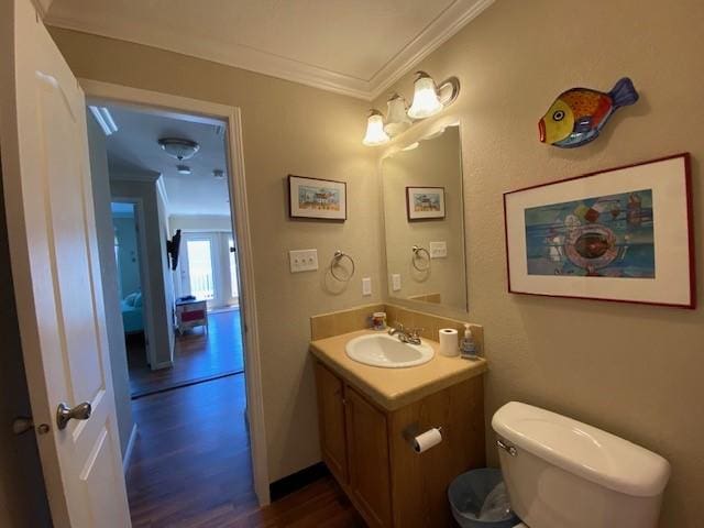 bathroom with ornamental molding, vanity, toilet, and wood finished floors