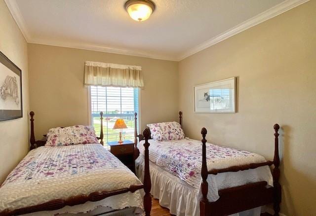 bedroom with ornamental molding and wood finished floors