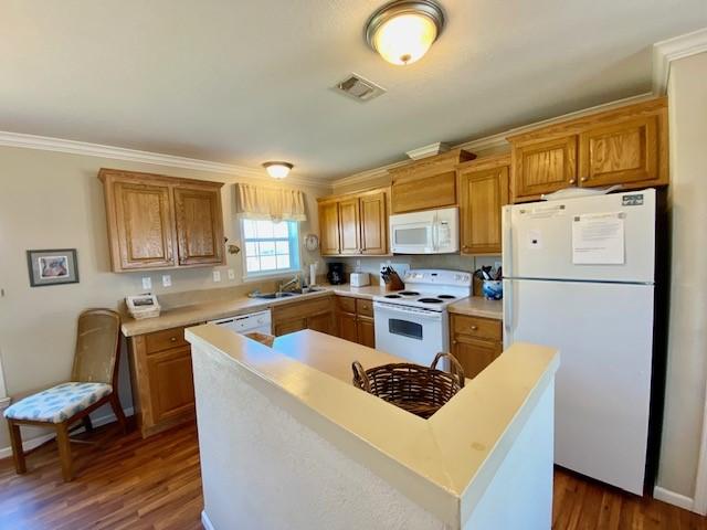 kitchen with white appliances, a sink, visible vents, light countertops, and dark wood-style floors