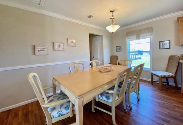 dining area featuring dark wood-type flooring, visible vents, crown molding, and baseboards