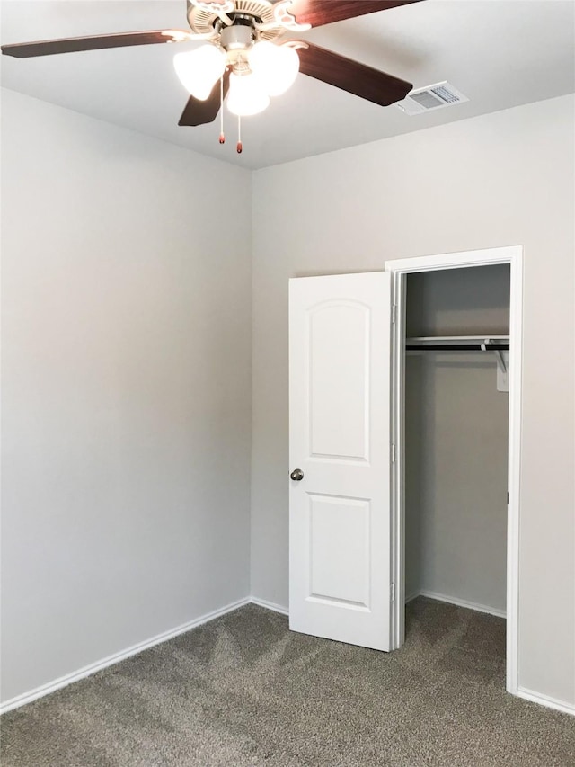 unfurnished bedroom featuring a closet, dark carpet, visible vents, and baseboards