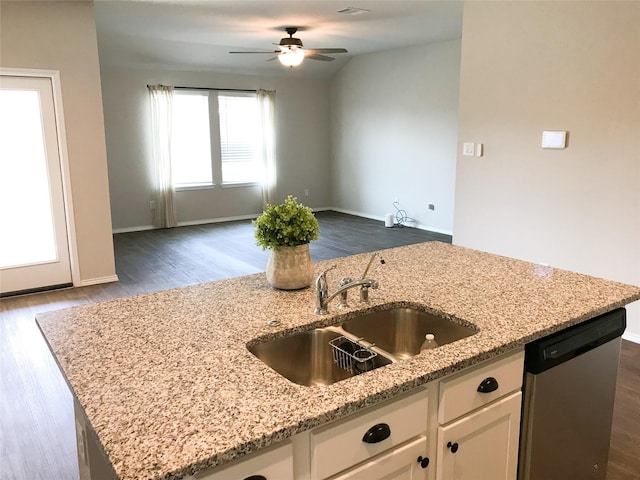 kitchen with open floor plan, white cabinets, a sink, light stone countertops, and dishwasher