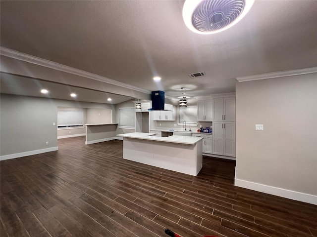 kitchen featuring a center island with sink, light countertops, visible vents, white cabinets, and exhaust hood