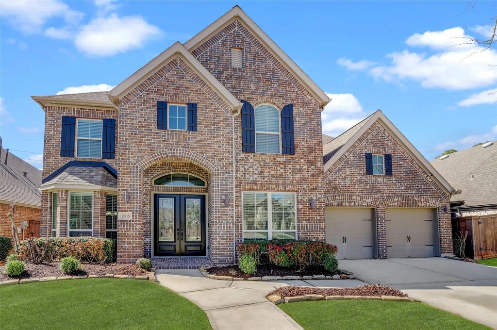 16815 Holtwood Oak Dr, Humble, TX 77346 - traditional-style house with brick siding, fence, concrete driveway, and french doors