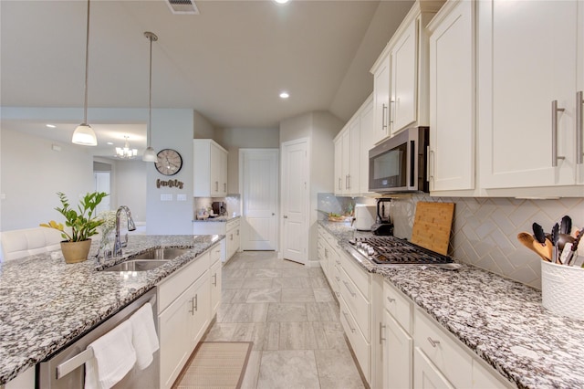 kitchen featuring light stone counters, a sink, white cabinets, hanging light fixtures, and appliances with stainless steel finishes