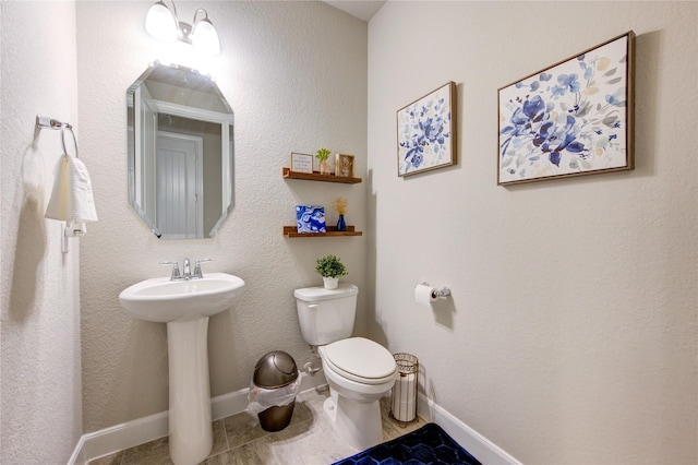 bathroom featuring baseboards, a sink, toilet, and tile patterned floors