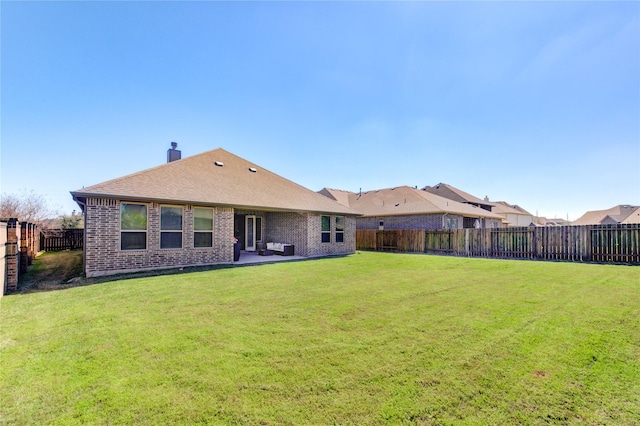 rear view of house featuring a patio area, a fenced backyard, brick siding, and a lawn