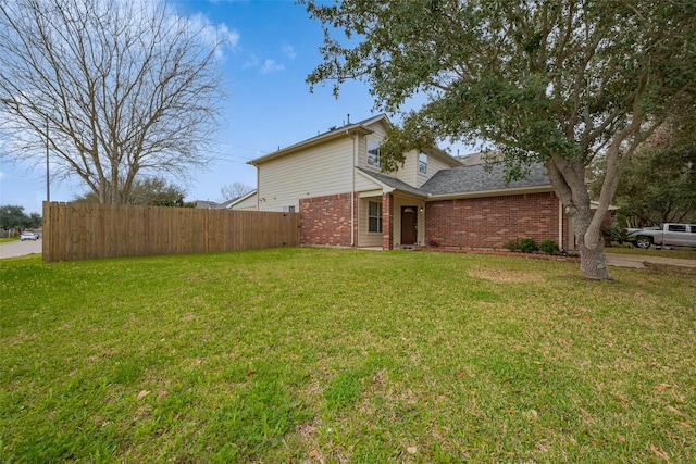 exterior space with a yard, brick siding, and fence