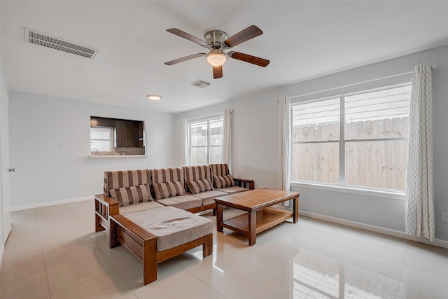 living room with a ceiling fan, visible vents, baseboards, and light tile patterned floors