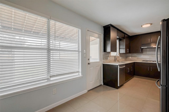 kitchen featuring light tile patterned floors, stainless steel appliances, light countertops, decorative backsplash, and under cabinet range hood