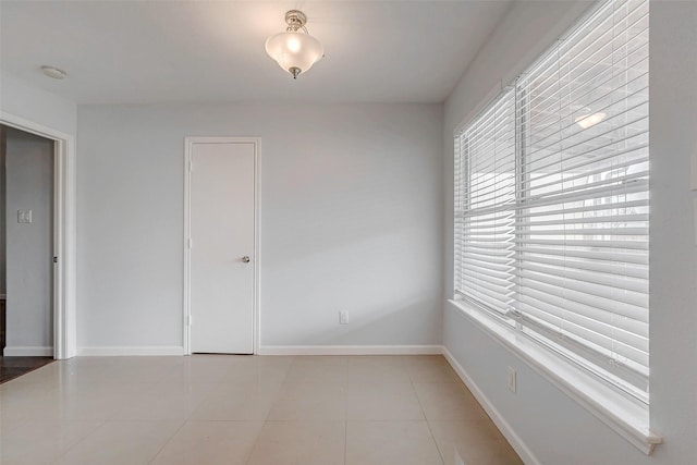 empty room featuring light tile patterned floors and baseboards