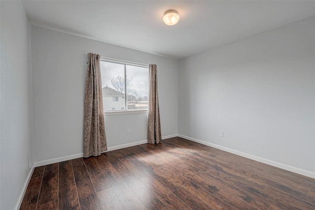 spare room with dark wood-style floors and baseboards