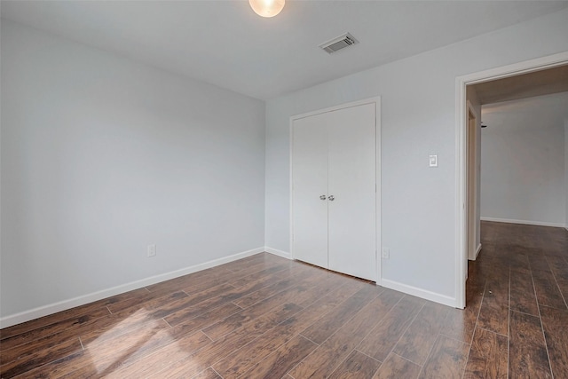 unfurnished bedroom featuring dark wood-style flooring, visible vents, and baseboards