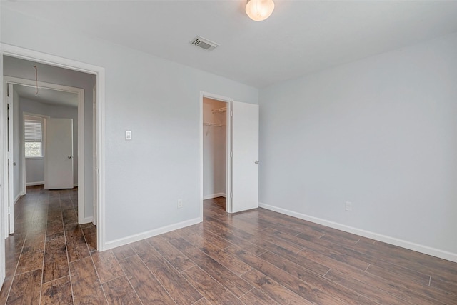 unfurnished bedroom with attic access, dark wood-style flooring, visible vents, and baseboards