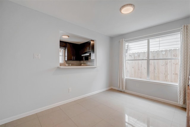 spare room with light tile patterned floors and baseboards