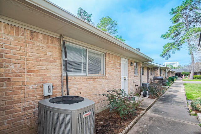 exterior space with central AC and brick siding