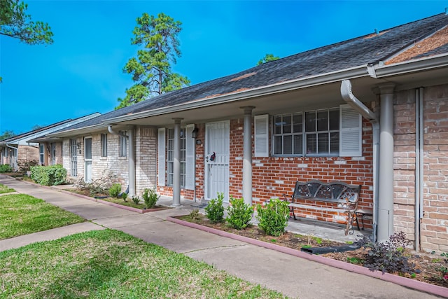 view of exterior entry featuring covered porch and brick siding