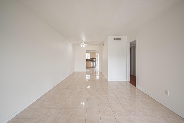 empty room featuring visible vents, light tile patterned flooring, a ceiling fan, and baseboards