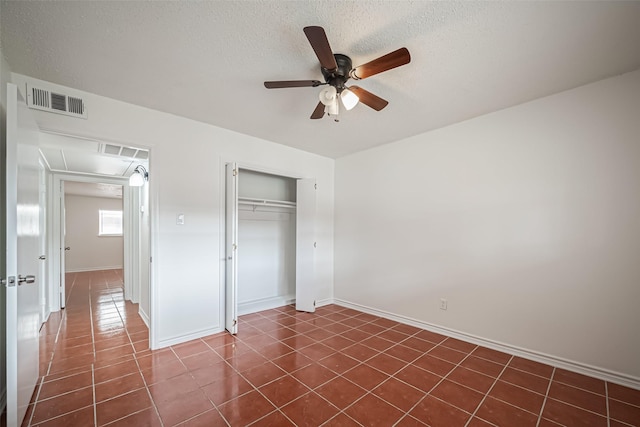 unfurnished bedroom featuring baseboards, visible vents, a textured ceiling, dark tile patterned floors, and a closet