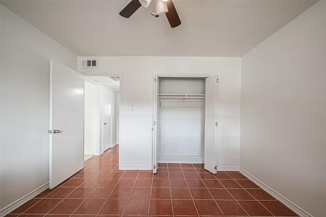 unfurnished bedroom with visible vents, dark tile patterned flooring, ceiling fan, a textured ceiling, and a closet