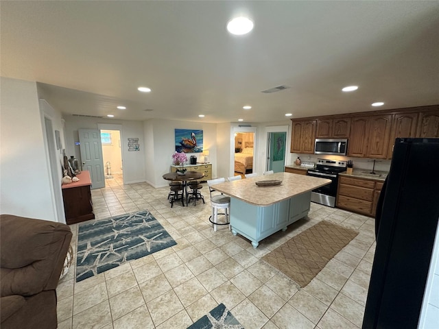 kitchen with visible vents, a kitchen island, appliances with stainless steel finishes, a sink, and recessed lighting