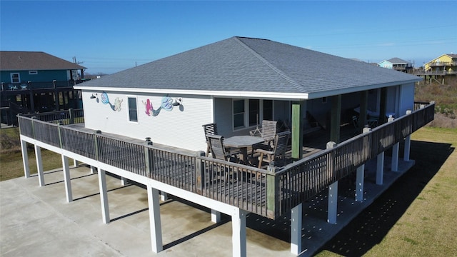 rear view of house featuring outdoor dining area and roof with shingles