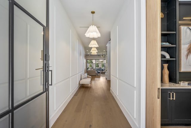 hallway featuring light wood finished floors and a decorative wall