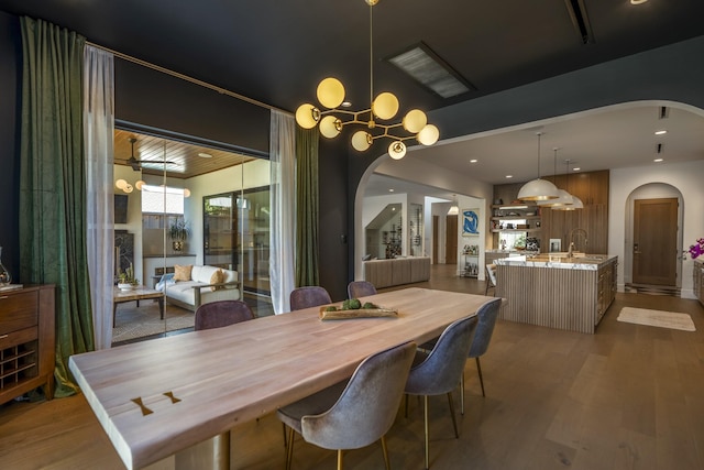 dining space featuring arched walkways, light wood-style flooring, and recessed lighting