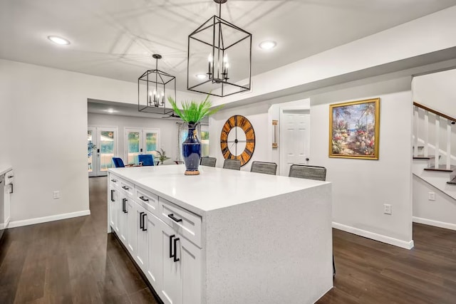 kitchen with white cabinets, a kitchen island, dark wood-style flooring, hanging light fixtures, and light countertops