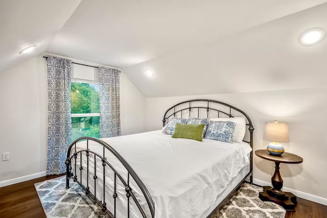 bedroom with dark wood-style flooring, vaulted ceiling, and baseboards