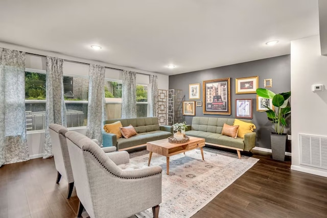 living area with dark wood-type flooring, visible vents, and baseboards