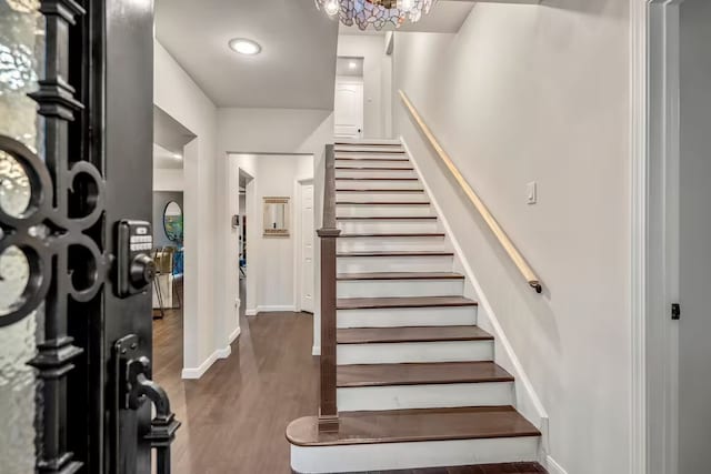 foyer entrance with stairs, dark wood-type flooring, and baseboards