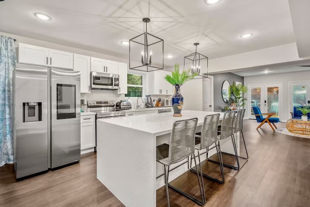 kitchen with a kitchen island, appliances with stainless steel finishes, white cabinets, and a kitchen breakfast bar