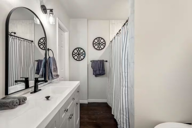 full bath featuring baseboards, wood finished floors, and vanity