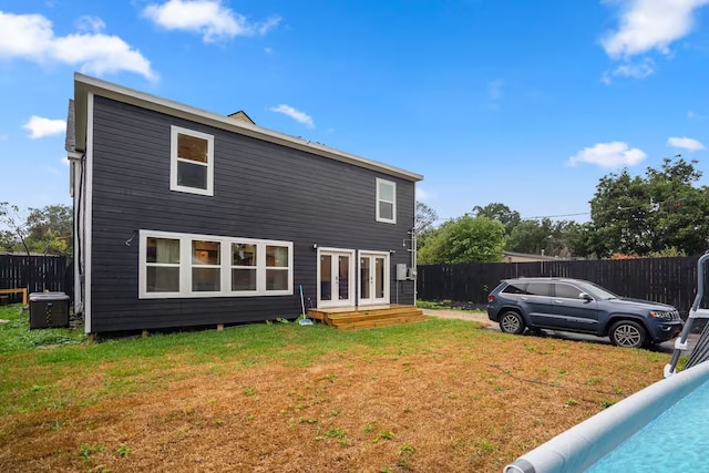 rear view of property featuring entry steps, cooling unit, fence, and a lawn