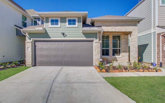 prairie-style home featuring stone siding, a shingled roof, and concrete driveway