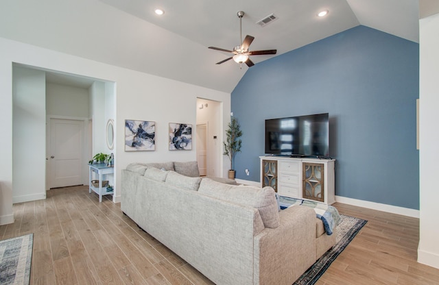 living area featuring baseboards, visible vents, a ceiling fan, vaulted ceiling, and light wood-type flooring