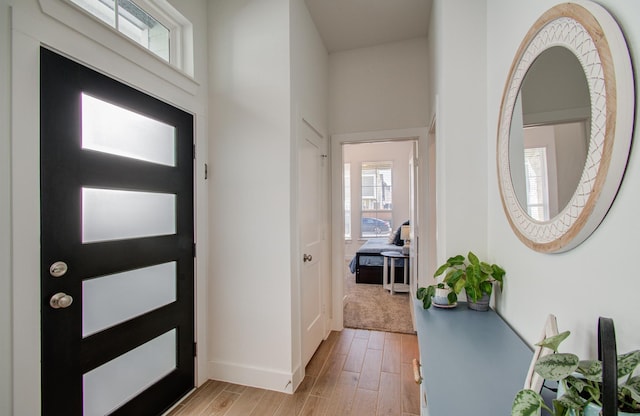 entrance foyer featuring light wood finished floors, a towering ceiling, and baseboards